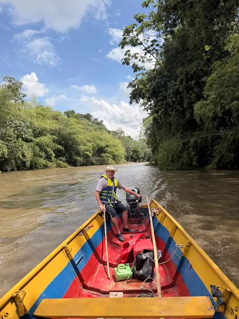 Der Kanuführer mit Hut und Schwimmweste auf einem von Bambus gesäumten Fluss